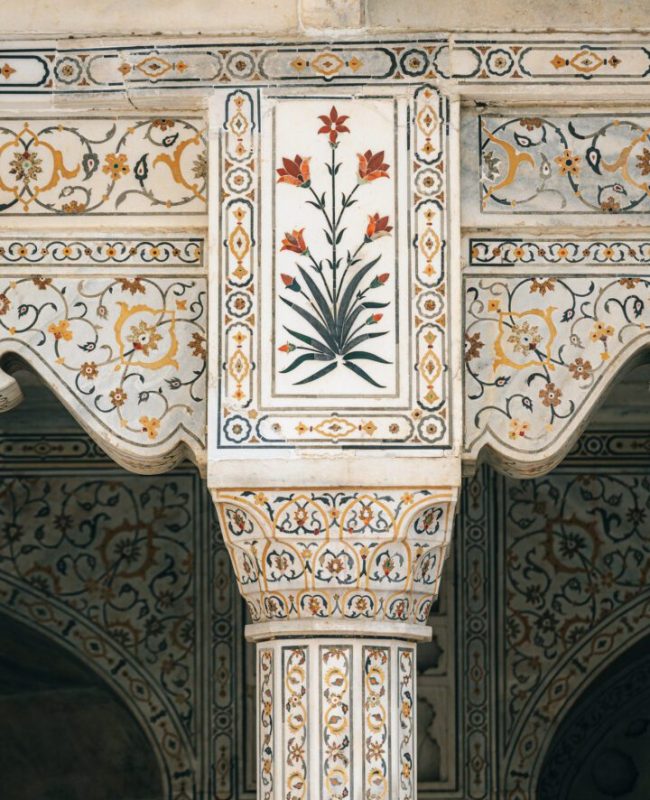 A close-up view of an elaborately ornamented column featuring colorful floral motifs, highlighting the luxurious Mughal era craftsmanship at Agra Fort, a significant heritage site in Agra, India.